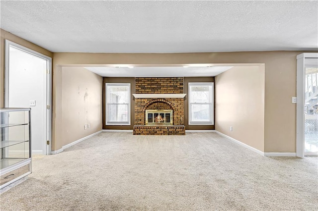 unfurnished living room featuring carpet, a textured ceiling, a fireplace, and baseboards