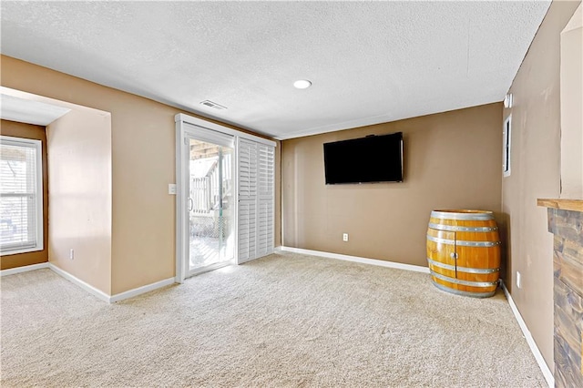 unfurnished living room featuring carpet flooring, a textured ceiling, and baseboards