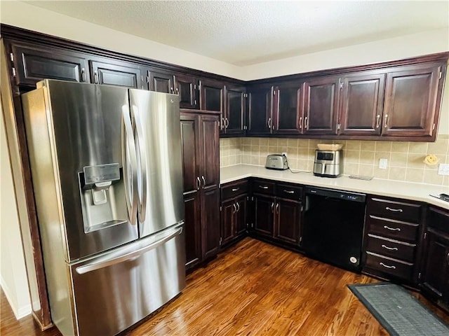 kitchen featuring stainless steel fridge, light countertops, black dishwasher, and dark wood-style flooring