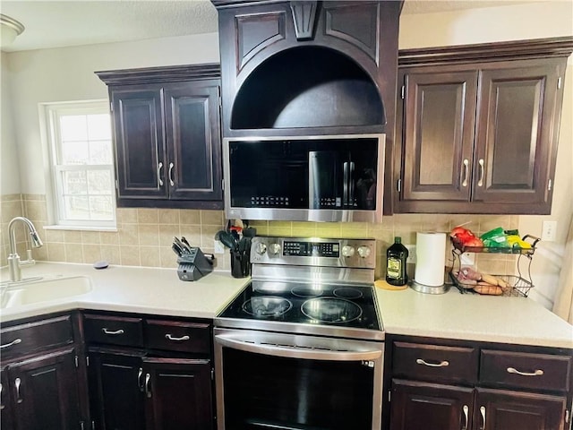 kitchen with a sink, decorative backsplash, light countertops, dark brown cabinetry, and stainless steel appliances