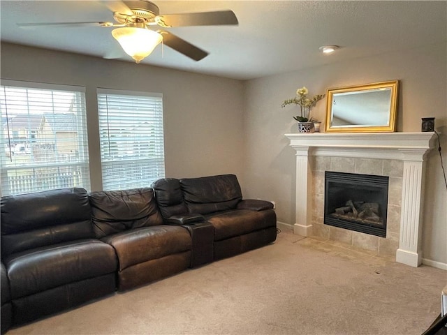 carpeted living room featuring baseboards, a ceiling fan, and a tile fireplace