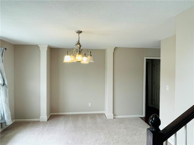 unfurnished room featuring baseboards, a chandelier, light colored carpet, a textured ceiling, and ornate columns