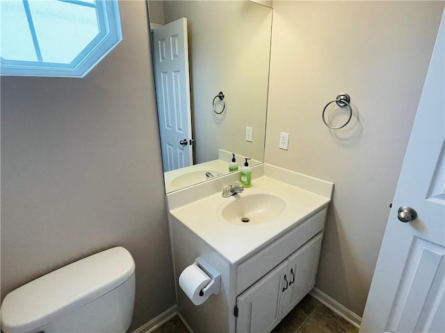 half bath featuring vanity, toilet, and baseboards