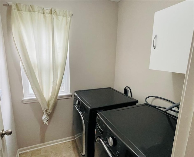 clothes washing area with baseboards, independent washer and dryer, and laundry area