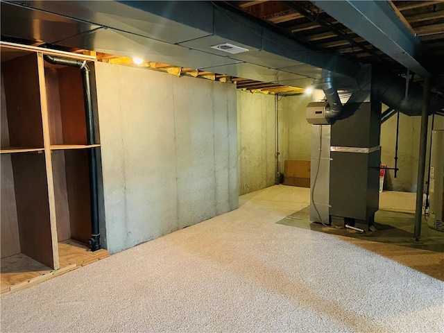 unfinished basement with visible vents and heating unit