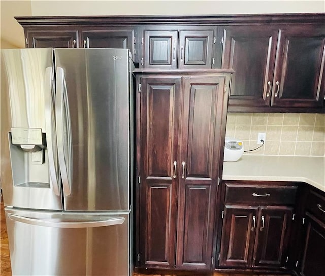 kitchen with light countertops, tasteful backsplash, stainless steel refrigerator with ice dispenser, and dark brown cabinets