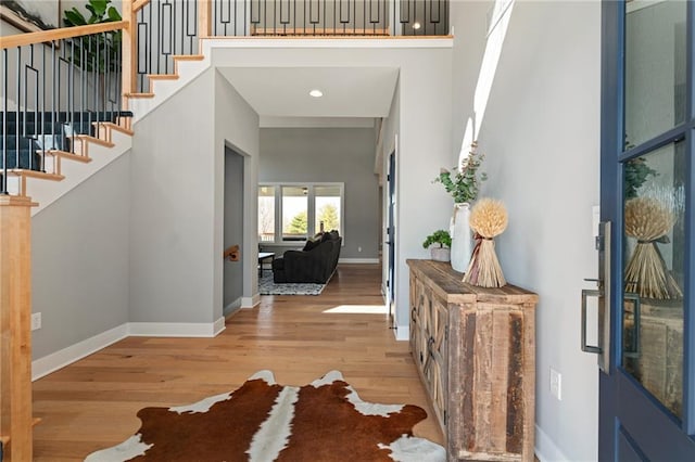 entrance foyer featuring stairway, a high ceiling, baseboards, and wood finished floors