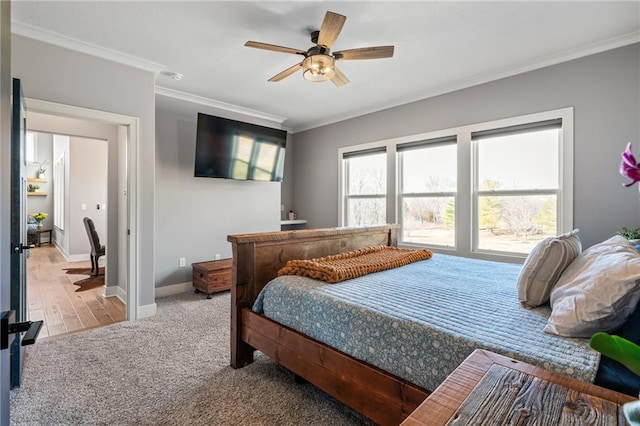 carpeted bedroom with a ceiling fan, crown molding, and baseboards