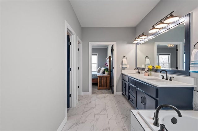 full bath featuring plenty of natural light, marble finish floor, ensuite bathroom, and a sink