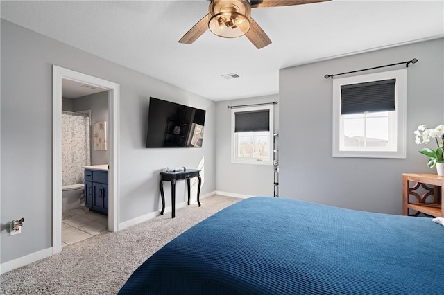 bedroom featuring visible vents, baseboards, light colored carpet, and ensuite bathroom