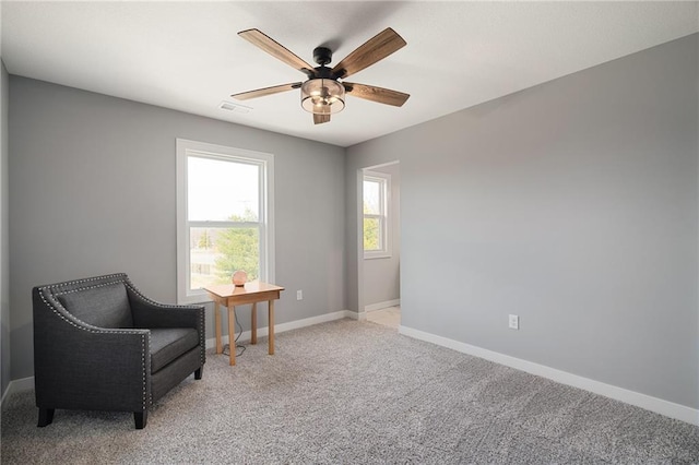 living area featuring a ceiling fan, baseboards, visible vents, and light carpet