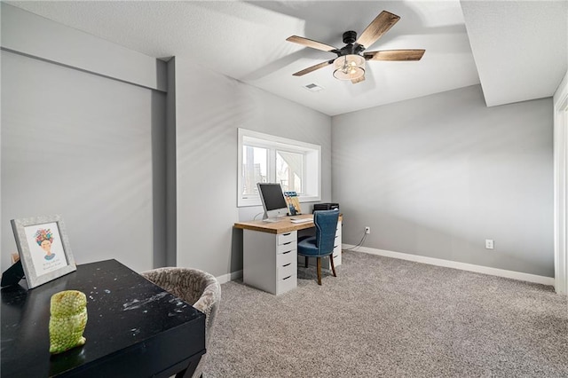 office area with light carpet, a textured ceiling, a ceiling fan, and baseboards