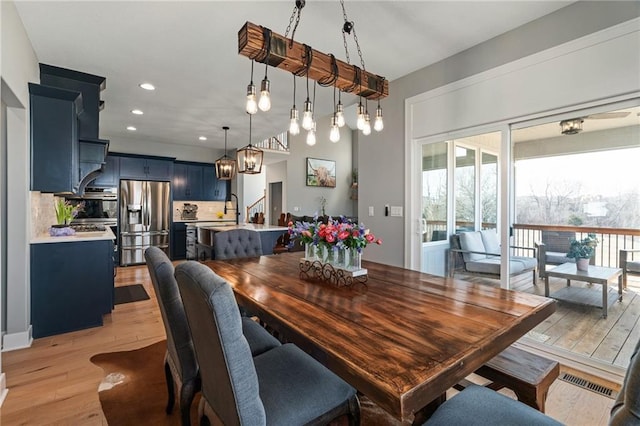 dining space with light wood finished floors, visible vents, recessed lighting, and stairs