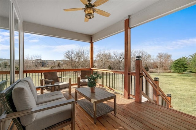 wooden deck with an outdoor living space, a lawn, and a ceiling fan