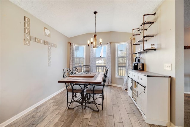 dining area with lofted ceiling, light wood-style floors, baseboards, and an inviting chandelier