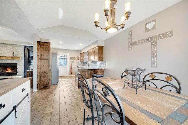 kitchen with light countertops, light wood-style floors, freestanding refrigerator, vaulted ceiling, and a chandelier