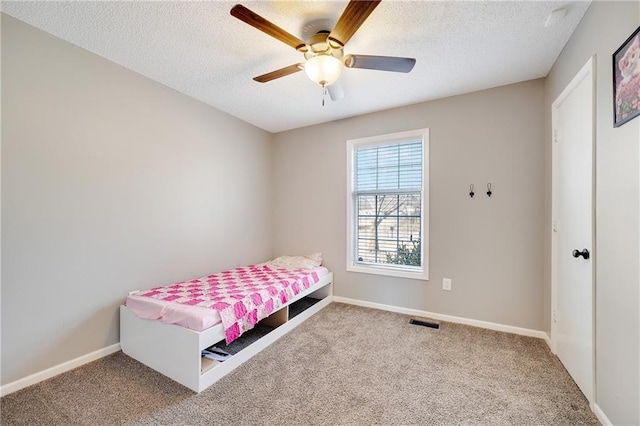 carpeted bedroom featuring a textured ceiling, a ceiling fan, visible vents, and baseboards