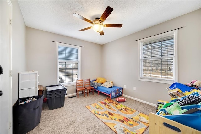 rec room featuring ceiling fan, a textured ceiling, baseboards, and carpet flooring