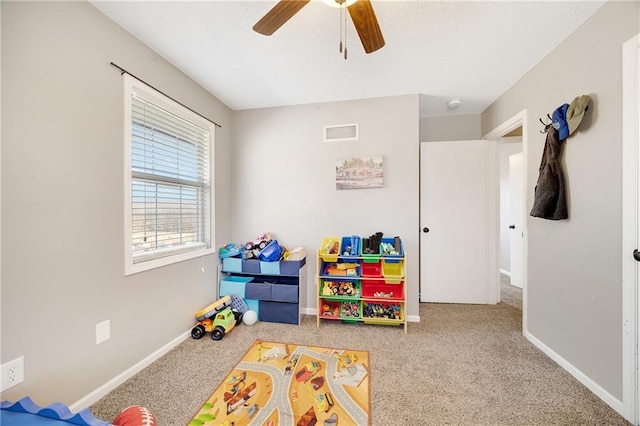 recreation room featuring carpet floors, a ceiling fan, visible vents, and baseboards