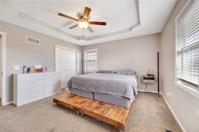 bedroom featuring a closet, a raised ceiling, visible vents, and baseboards