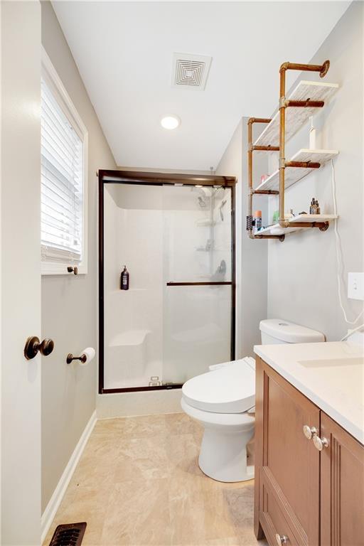 bathroom featuring toilet, a stall shower, vanity, and visible vents