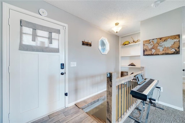 entrance foyer featuring a textured ceiling, baseboards, and wood finished floors