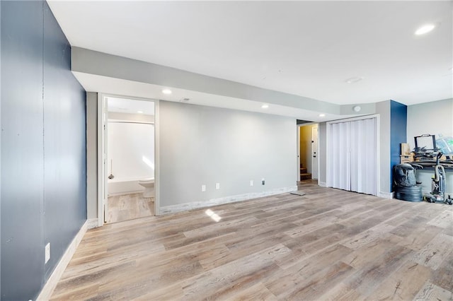 finished basement featuring light wood-style floors, stairway, baseboards, and recessed lighting