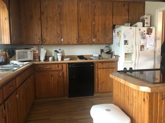 kitchen with white appliances, a sink, wood finished floors, backsplash, and brown cabinets