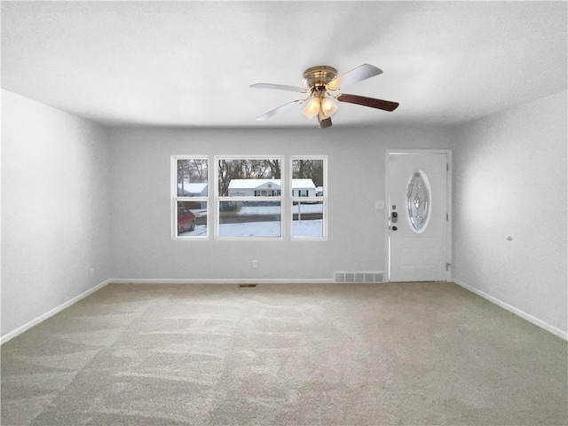 carpeted empty room featuring a ceiling fan, visible vents, and baseboards