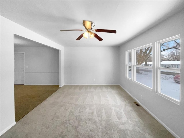 carpeted spare room featuring a ceiling fan, visible vents, and baseboards