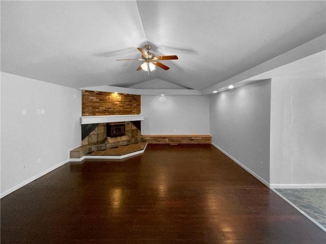 unfurnished living room with lofted ceiling, a large fireplace, ceiling fan, and wood finished floors