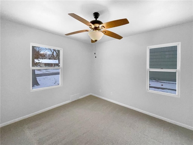 carpeted empty room with a ceiling fan, visible vents, and baseboards