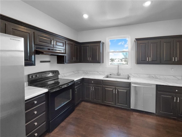 kitchen featuring appliances with stainless steel finishes, a sink, dark wood finished floors, and under cabinet range hood