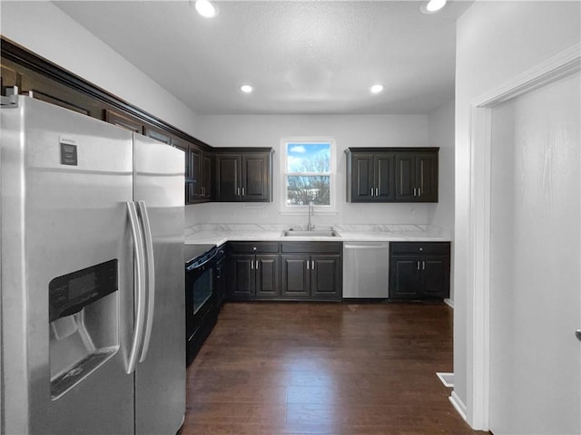 kitchen featuring dark wood-style flooring, recessed lighting, light countertops, appliances with stainless steel finishes, and a sink