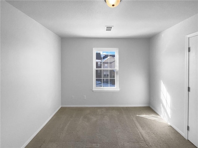 unfurnished room with carpet floors, visible vents, and baseboards