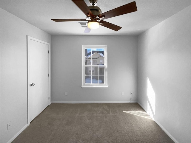 unfurnished room with ceiling fan, carpet flooring, visible vents, and baseboards