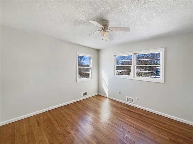 spare room with visible vents, baseboards, and wood finished floors