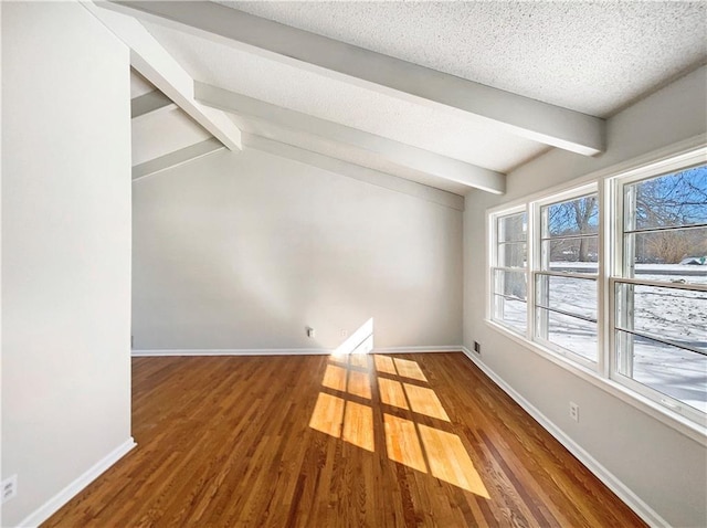 empty room featuring a textured ceiling, wood finished floors, and baseboards