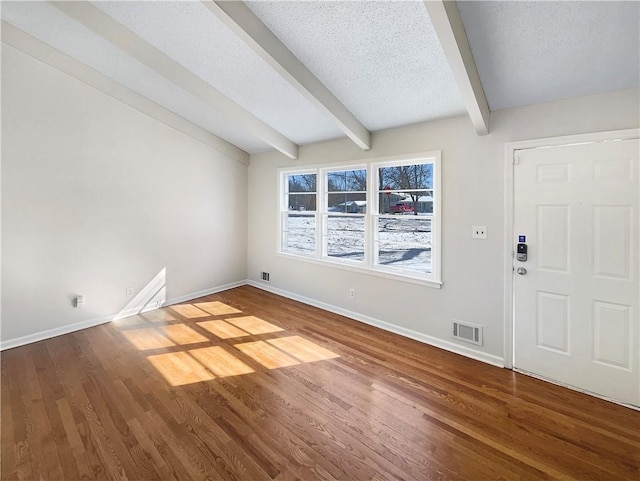 entrance foyer featuring visible vents, a textured ceiling, baseboards, and wood finished floors