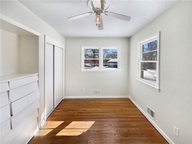 unfurnished bedroom featuring visible vents, a textured ceiling, and wood finished floors