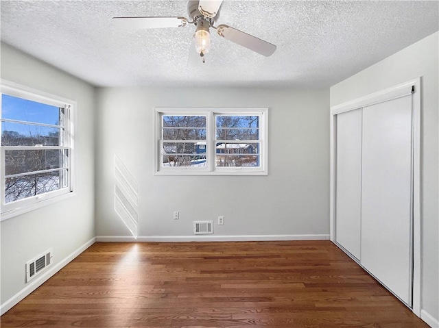 unfurnished bedroom with a closet, visible vents, and wood finished floors