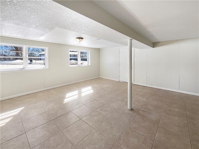 below grade area featuring a textured ceiling, baseboards, and tile patterned floors