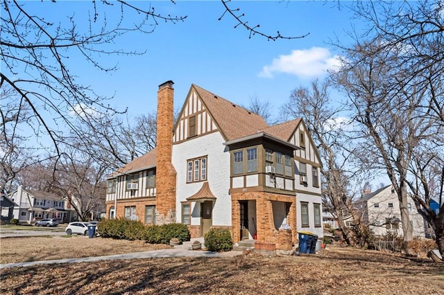 view of front facade with brick siding, a chimney, a residential view, and stucco siding