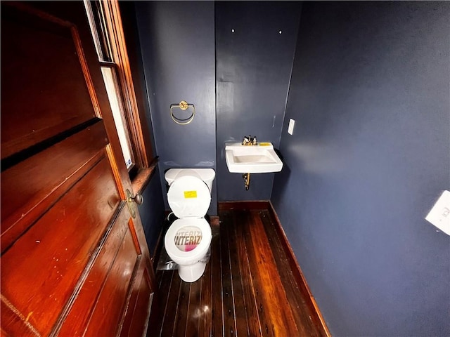 bathroom featuring wood finished floors, a sink, toilet, and baseboards