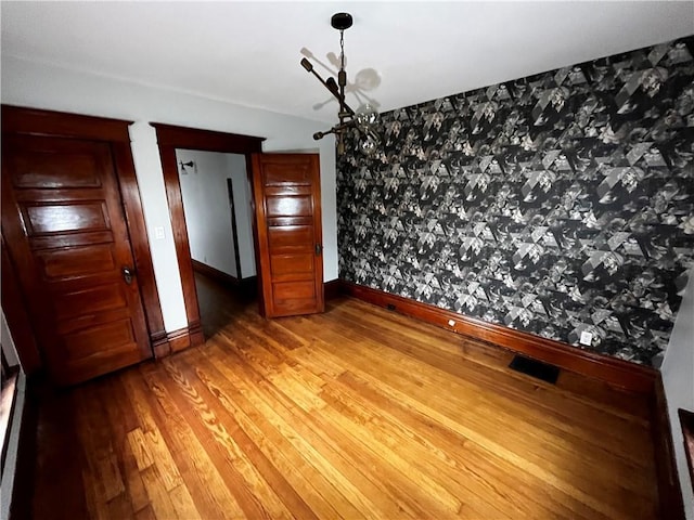 unfurnished bedroom featuring baseboards, visible vents, and wood finished floors