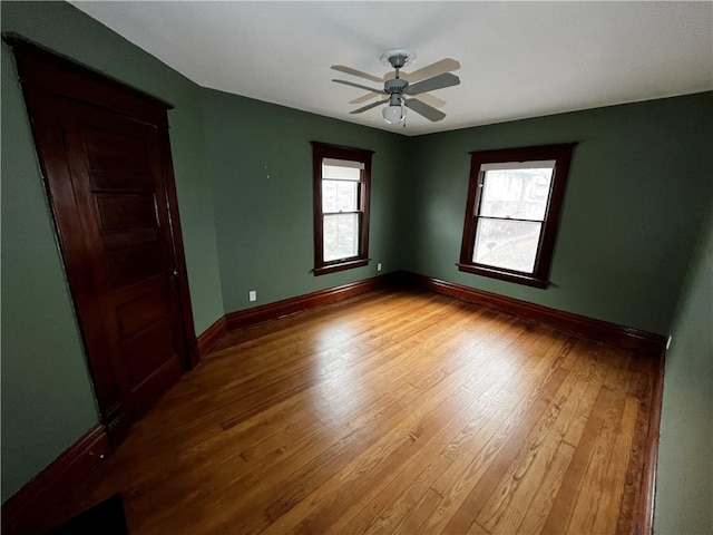 empty room featuring ceiling fan, wood finished floors, and baseboards