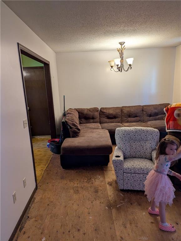 living room with baseboards, a textured ceiling, a chandelier, and hardwood / wood-style flooring