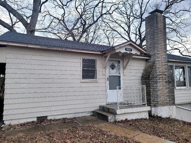 property entrance featuring a shingled roof and crawl space