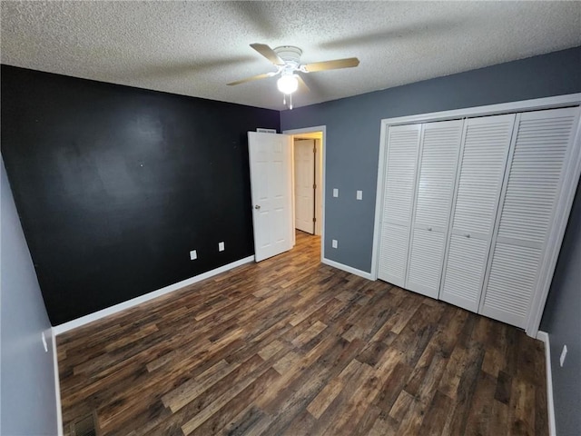 unfurnished bedroom featuring a textured ceiling, a ceiling fan, baseboards, a closet, and dark wood finished floors