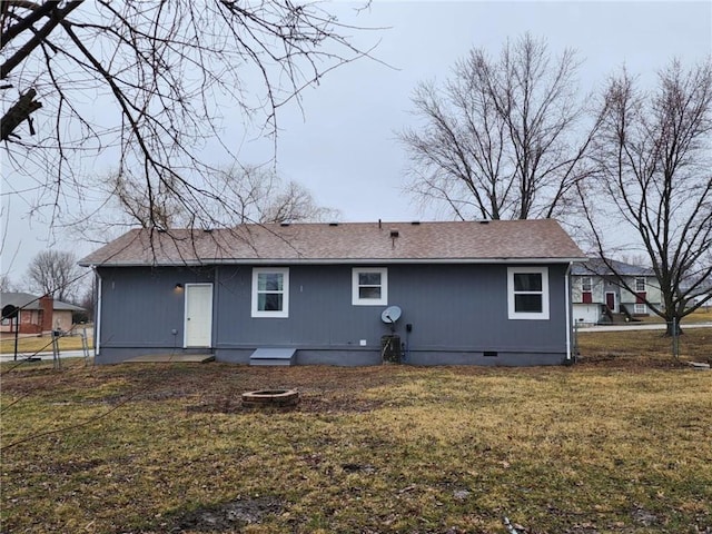 back of house featuring crawl space, a shingled roof, and a yard